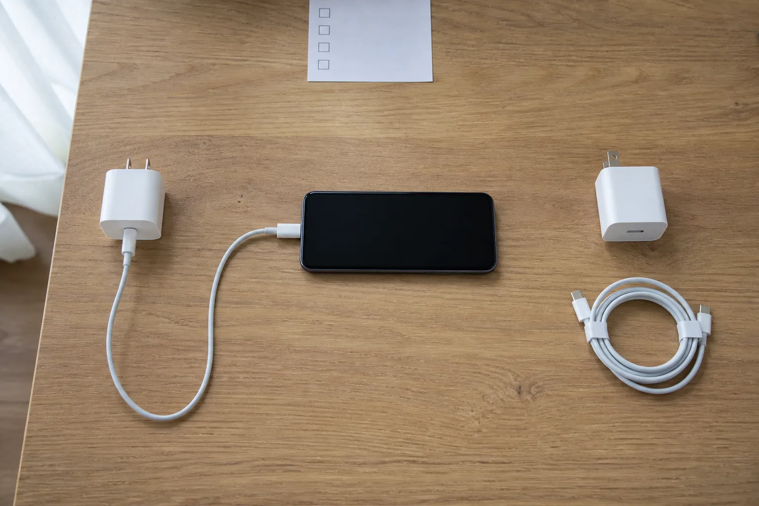 桌面上以同一支手機比較兩組充電器與線材，一次只更換一個變因的排查示意